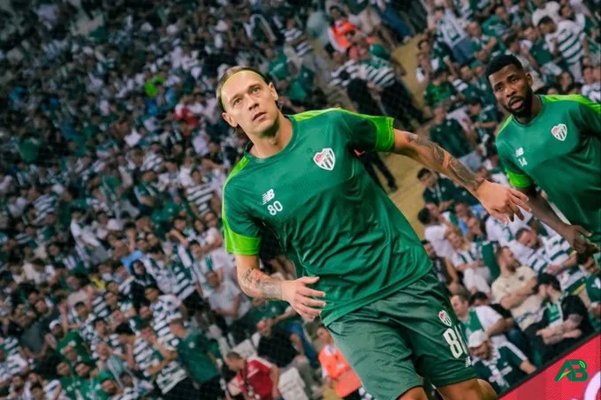 Bursaspor forması giyen Ivan Saranic ve takım arkadaşı yeşil beyazlı formalarıyla sahada yürüyor.
